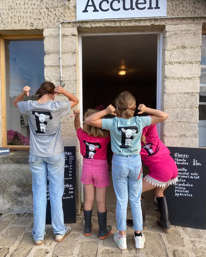 Quatre enfants en tee-shirt de la Foucaudière devant la fenêtre de l'accueil de la ferme
