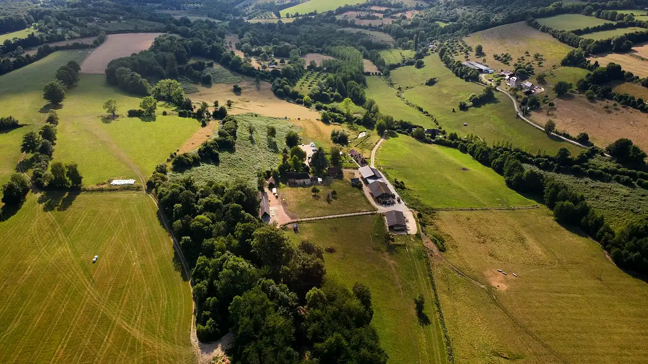 La ferme de la Foucaudière vue du ciel : ses prairies, ses haies bocagères et les collines du Pays d'Auge