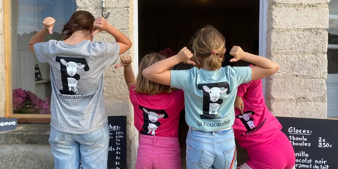 Quatre enfants en t-shirt de la Foucaudière devant la porte de l'accueil de la ferme